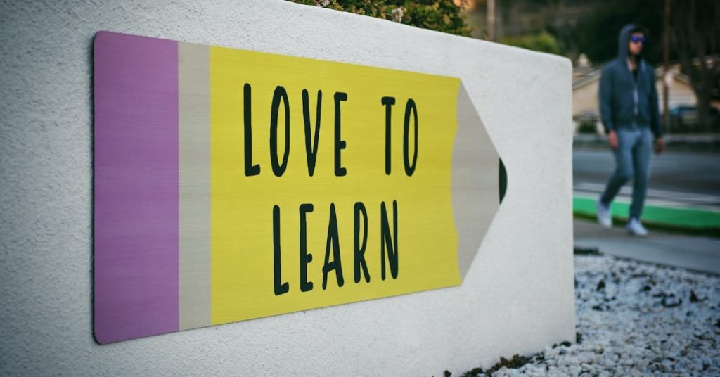 Image of a colourful sign in the shape of a pencil on a wall with the text 'Love to Learn' displayed.